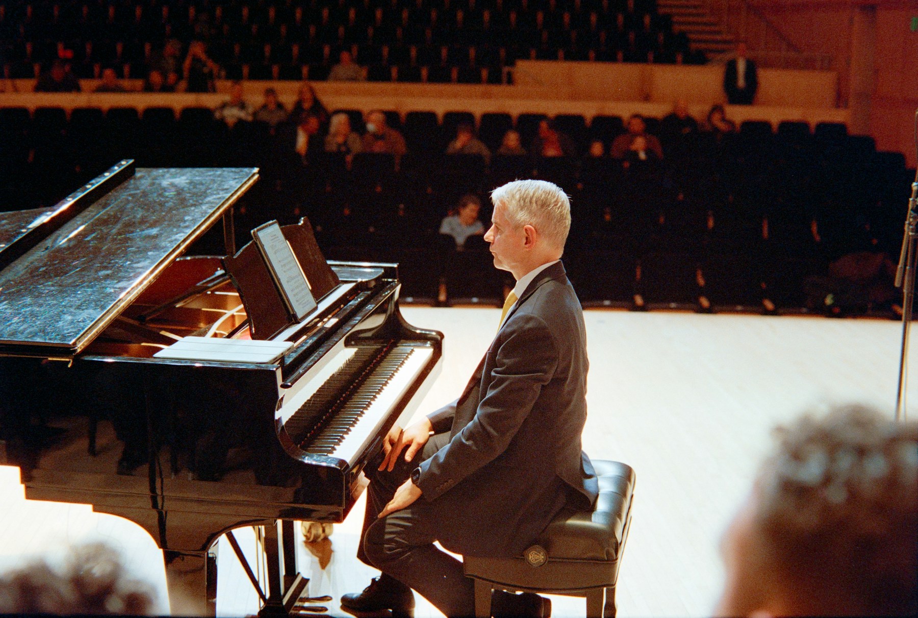 A pianist seated at a grand piano on a concert stage